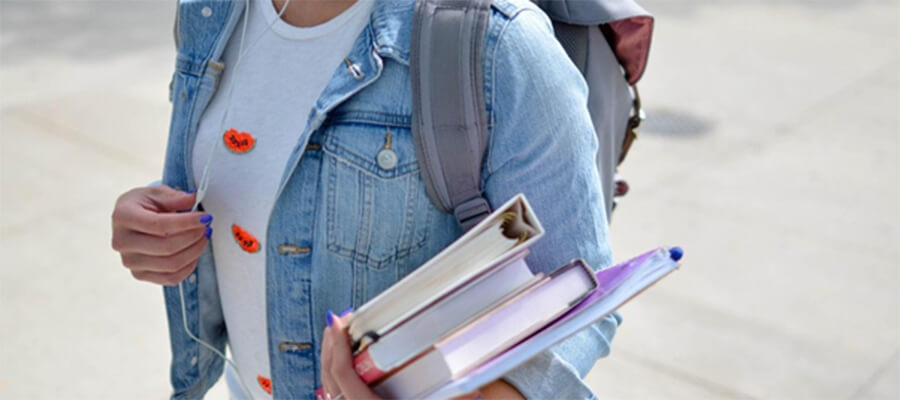 University student holding books and folders.